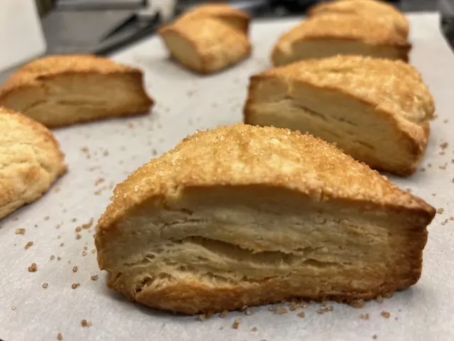 Freshly baked pastries with flaky, layered edges cooling on parchment.