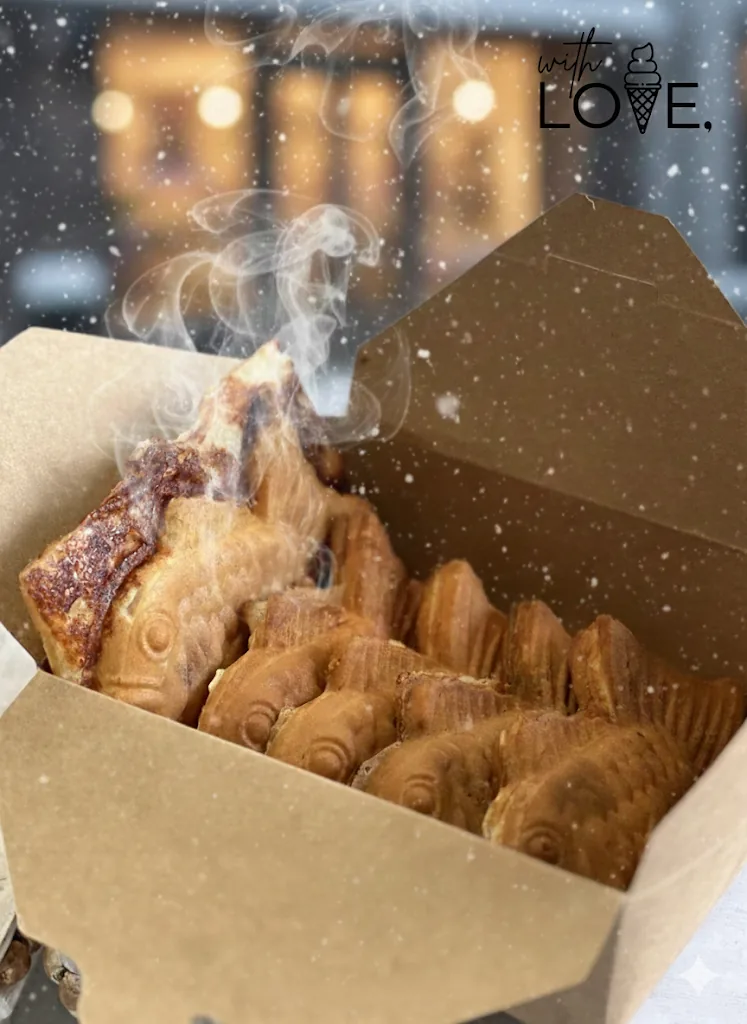 A takeout box packed with hot taiyaki, steam rising, on a snowy evening.